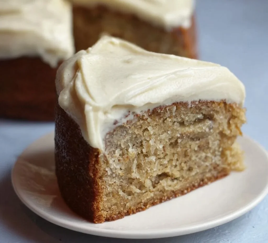 Slice of banana cake with spiced vanilla buttercream on a plate