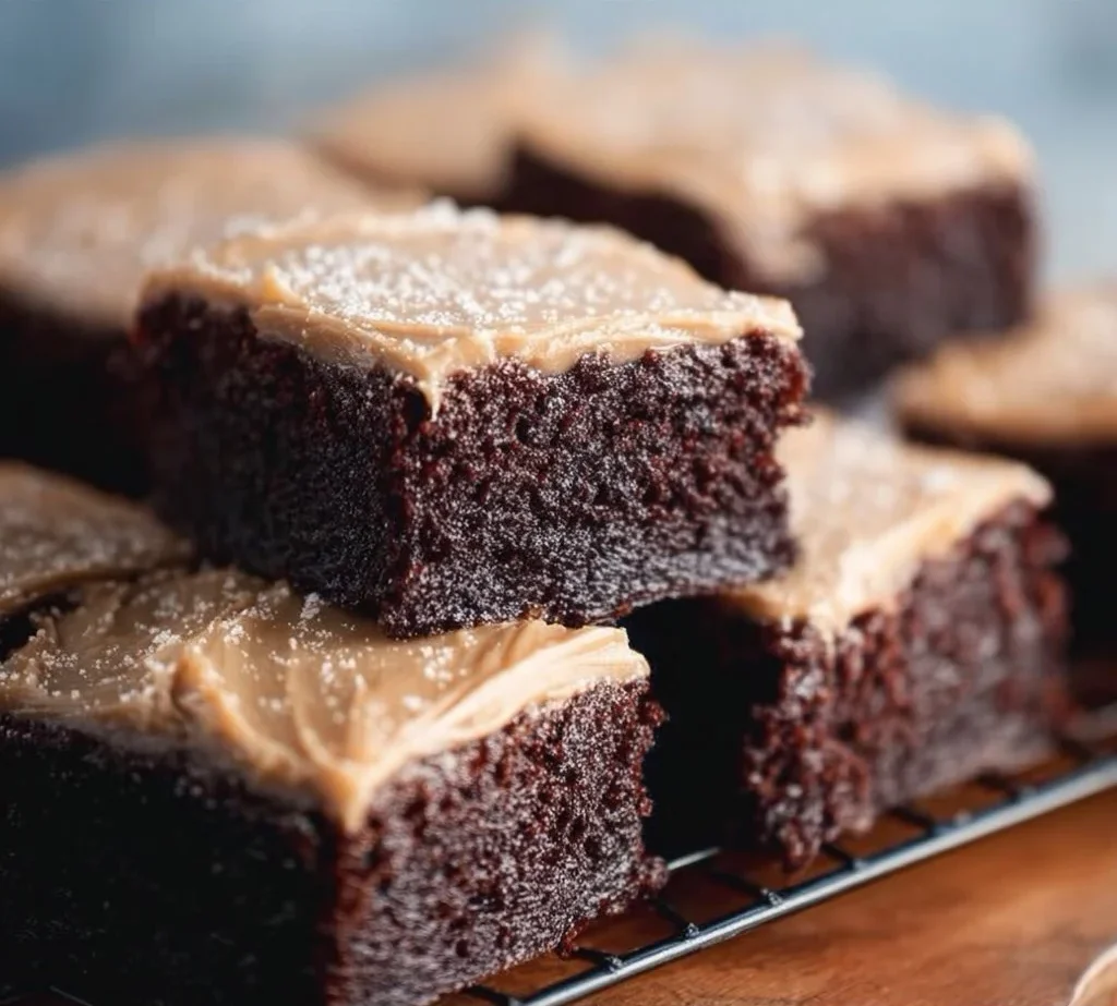 Delicious frosted coffee brownies topped with creamy frosting on a wooden table