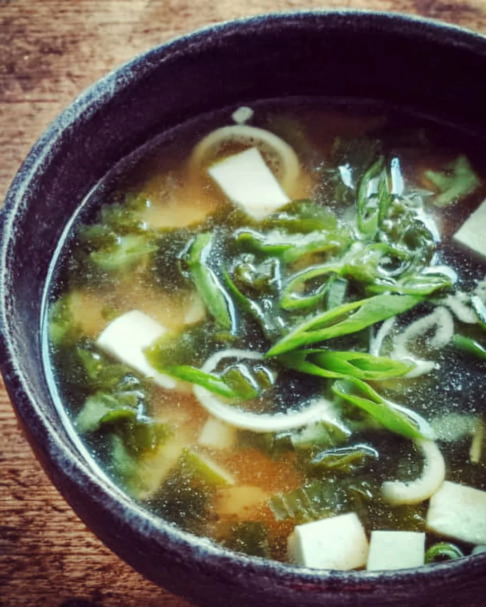 A steaming bowl of homemade miso soup with tofu and green onions