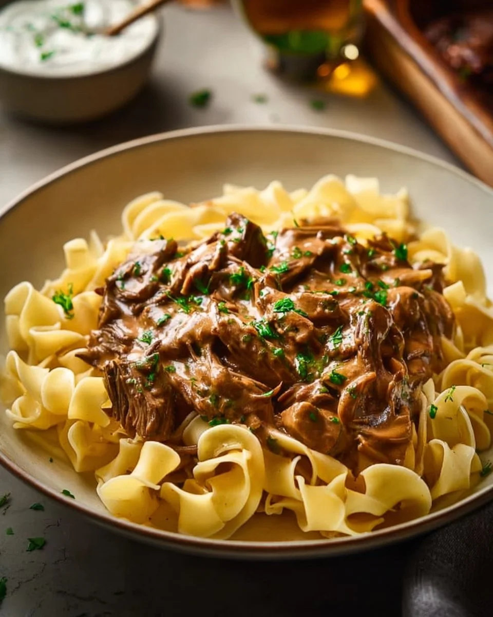 Delicious classic beef stroganoff served in a bowl with noodles and garnished with parsley.